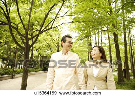 Couple taking a walk at a park View Large Photo Image Stock Photo - Couple taking a walk at a park. Fotosearch