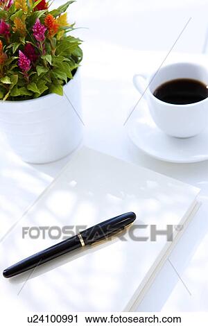Stock Image - Cup of coffee and potted plant by book and pen, white background. Fotosearch