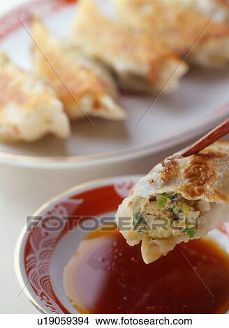 Picture - Dipping gyoza, fried Chinese-style dumplings, into soy sauce. Fotosearch