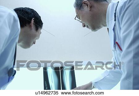 Stock Photography - Doctors discussing X-rays, white background. Fotosearch