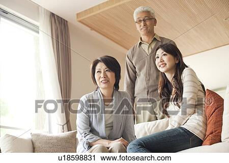 Stock Image - Family in living room, mother and daughter sitting on sofa. Fotosearch