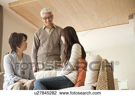 Stock Image - Family in living room, mother and daughter sitting on sofa. Fotosearch