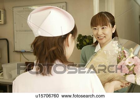 Female nurse giving flower bouquet to woman View Large Photo Image Stock Image - Female nurse giving flower bouquet to woman. Fotosearch