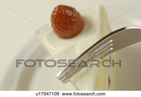 Stock Photo - Fork on sliced strawberry cake, close up, white background. Fotosearch