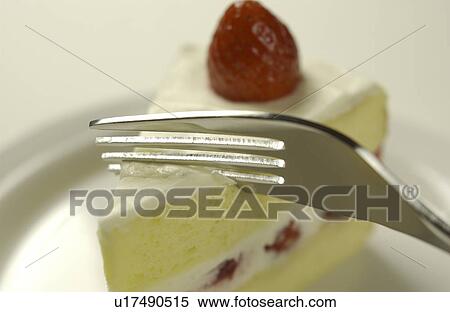 Stock Photography - Fork on sliced strawberry cake, close up, white background. Fotosearch