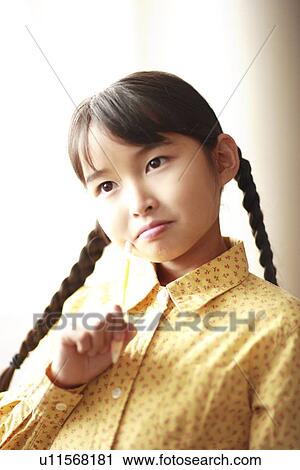 Stock Image - Girl putting head on pencil, Kobe city, Hyogo prefecture, Japan. Fotosearch