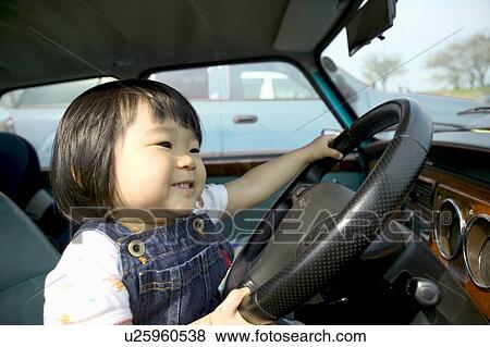 Stock Photo - Girl smiling in car, holding steering wheel. Fotosearch