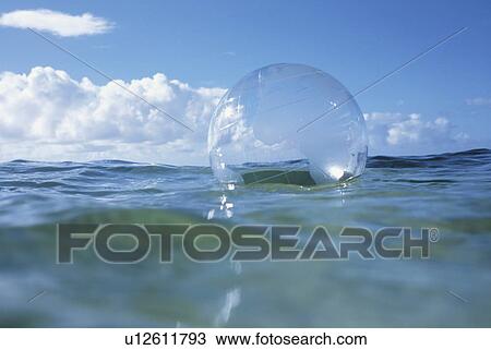 Stock Image - Globe beach ball floating on water. Fotosearch