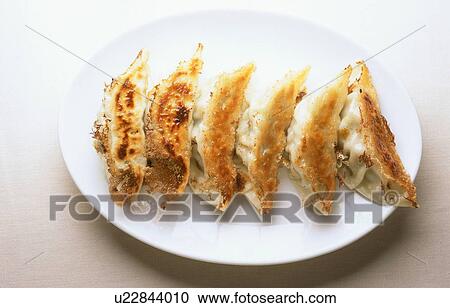 Gyoza, fried Chinese-style dumplings, served on a plate View Large Photo Image Stock Image - Gyoza, fried Chinese-style dumplings, served on a plate. Fotosearch
