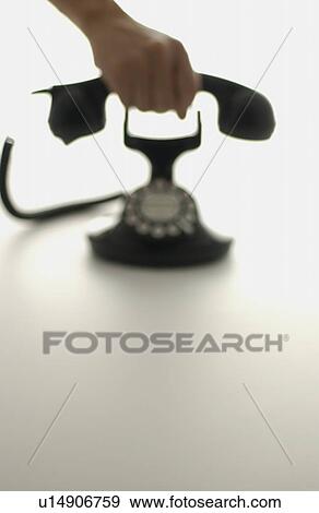 Stock Photo - Hand holding telephone receiver, white background, defocused. Fotosearch