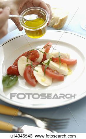 Hand pouring olive oil on tomatoes, mozzarella and basil salad View Large Photo Image Stock Image - Hand pouring olive oil on tomatoes, mozzarella and basil salad. Fotosearch