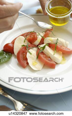 Hand pouring olive oil on tomatoes, mozzarella and basil salad View Large Photo Image Stock Photo - Hand pouring olive oil on tomatoes, mozzarella and basil salad. Fotosearch