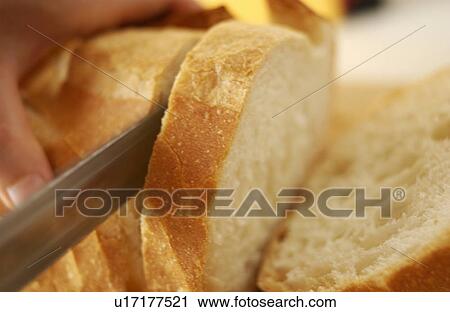 Stock Image - Hand slicing bread. Fotosearch