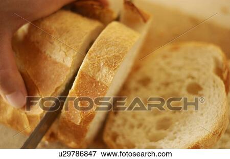 Stock Photo - Hand slicing bread. Fotosearch