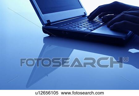 Stock Photography - Hand using laptop, blue background. Fotosearch