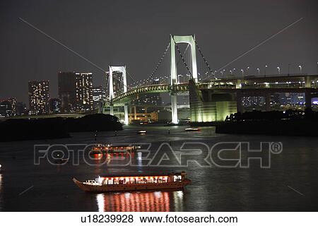 Stock Photo - Illuminated Rainbow Bridge and boats in the night, long exposure, Tokyo prefecture, Japan. Fotosearch