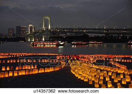 Stock Image - Illuminated Rainbow Bridge and boats, lanterns floating on Tokyo Bay, long exposure, Tokyo prefecture, Japan. Fotosearch