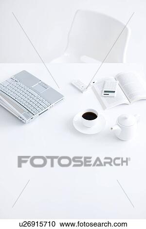 Stock Image - Laptop and cup of coffee on desk in office, white background. Fotosearch