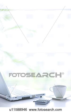 Stock Photograph - Laptop and cup of coffee on desk in office, differential focus. Fotosearch