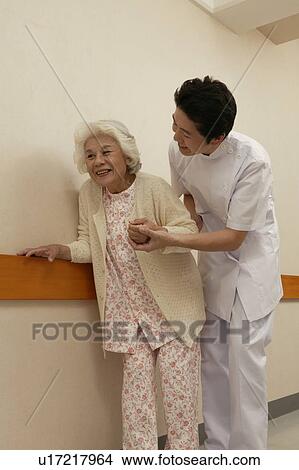 Picture - Male nurse helping senior woman walking in corridor. Fotosearch