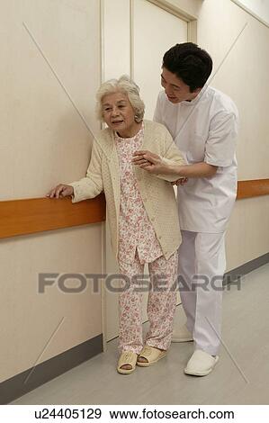 Male nurse helping senior woman walking in corridor View Large Photo Image Stock Photo - Male nurse helping senior woman walking in corridor. Fotosearch