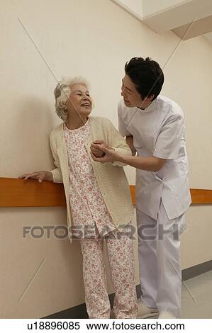 Male nurse helping senior woman walking in corridor View Large Photo Image Stock Photography - Male nurse helping senior woman walking in corridor. Fotosearch