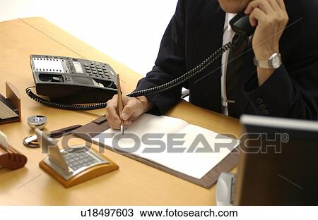 Stock Image - Man in Business Suit Holding a Pen, Talking on the Phone. Fotosearch