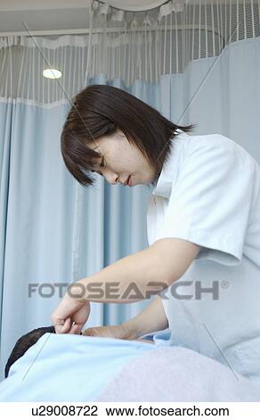 Stock Image - Massage therapist massaging man's back. Fotosearch