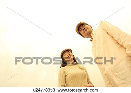 Stock Image - Mature couple standing, low angle view. Fotosearch