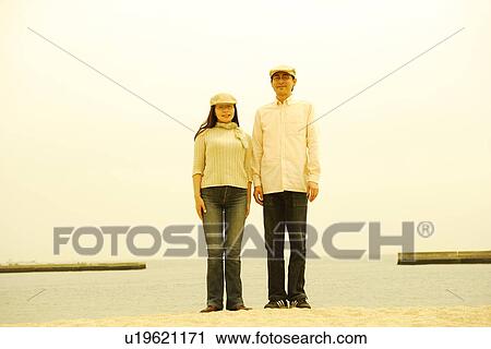 Stock Image - Mature couple standing on beach. Fotosearch