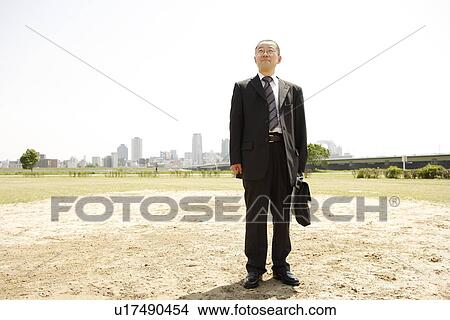 Picture - Mature man standing in empty lot, smiling and looking up. Fotosearch