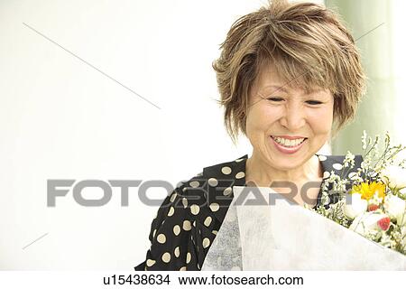 Mature woman holding flower bouquet, smiling View Large Photo Image Picture - Mature woman holding flower bouquet, smiling. Fotosearch