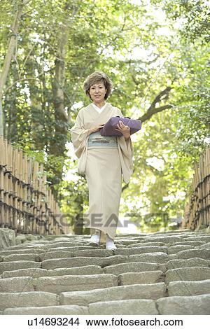 Mature woman in Kimono holding gift, walking down stairs, Kyoto city, Kyoto prefecture, Japan View Large Photo Image Picture - Mature woman in Kimono holding gift, walking down stairs, Kyoto city, Kyoto prefecture, Japan. Fotosearch