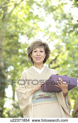 Mature woman in Kimono holding gift, smiling, Kyoto city, Kyoto prefecture, Japan View Large Photo Image Picture - Mature woman in Kimono holding gift, smiling, Kyoto city, Kyoto prefecture, Japan. Fotosearch