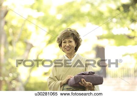 Mature woman in Kimono holding gift, smiling, Kyoto city, Kyoto prefecture, Japan View Large Photo Image Stock Photography - Mature woman in Kimono holding gift, smiling, Kyoto city, Kyoto prefecture, Japan. Fotosearch