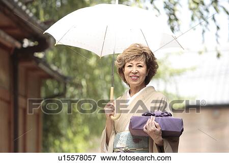 Mature woman in Kimono holding umbrella and gift, Kyoto city, Kyoto prefecture, Japan View Large Photo Image Stock Photo - Mature woman in Kimono holding umbrella and gift, Kyoto city, Kyoto prefecture, Japan. Fotosearch