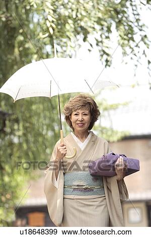 Mature woman in Kimono holding umbrella and gift, Kyoto city, Kyoto prefecture, Japan View Large Photo Image Stock Photo - Mature woman in Kimono holding umbrella and gift, Kyoto city, Kyoto prefecture, Japan. Fotosearch