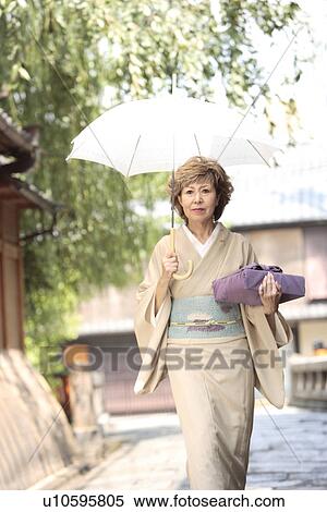 Mature woman in Kimono holding umbrella and gift, Kyoto city, Kyoto prefecture, Japan View Large Photo Image Stock Photography - Mature woman in Kimono holding umbrella and gift, Kyoto city, Kyoto prefecture, Japan. Fotosearch