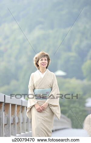Stock Image - Mature woman in Kimono walking on bridge, Kyoto city, Kyoto prefecture, Japan. Fotosearch