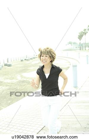 Mature woman jogging on beach, smiling View Large Photo Image Stock Photo - Mature woman jogging on beach, smiling. Fotosearch
