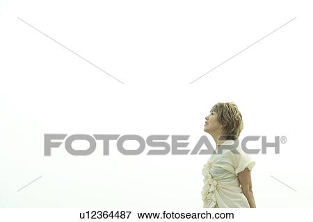 Stock Photo - Mature woman looking up to sky, white background, copy space. Fotosearch