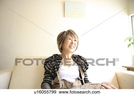 Mature woman sitting on sofa, smiling View Large Photo Image Stock Photo - Mature woman sitting on sofa, smiling. Fotosearch