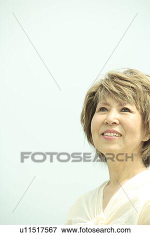 Stock Photo - Mature woman smiling, blue background, copy space. Fotosearch