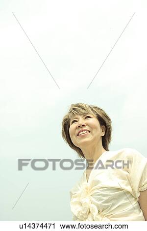 Mature woman smiling under sky, copy space View Large Photo Image Stock Image - Mature woman smiling under sky, copy space. Fotosearch