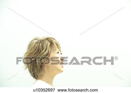 Stock Photo - Mature woman smiling under sky, copy space. Fotosearch