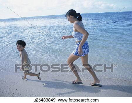 Stock Photo - Mother and son running on beach. Fotosearch