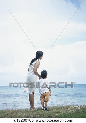 Stock Photography - Mother and son standing on beach. Fotosearch