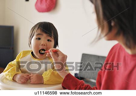 Stock Photo - Mother feeding baby boy. Fotosearch