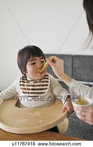 Stock Photo - Mother feeding baby boy. Fotosearch