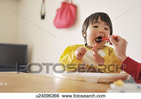 Stock Photograph - Mother feeding baby boy. Fotosearch